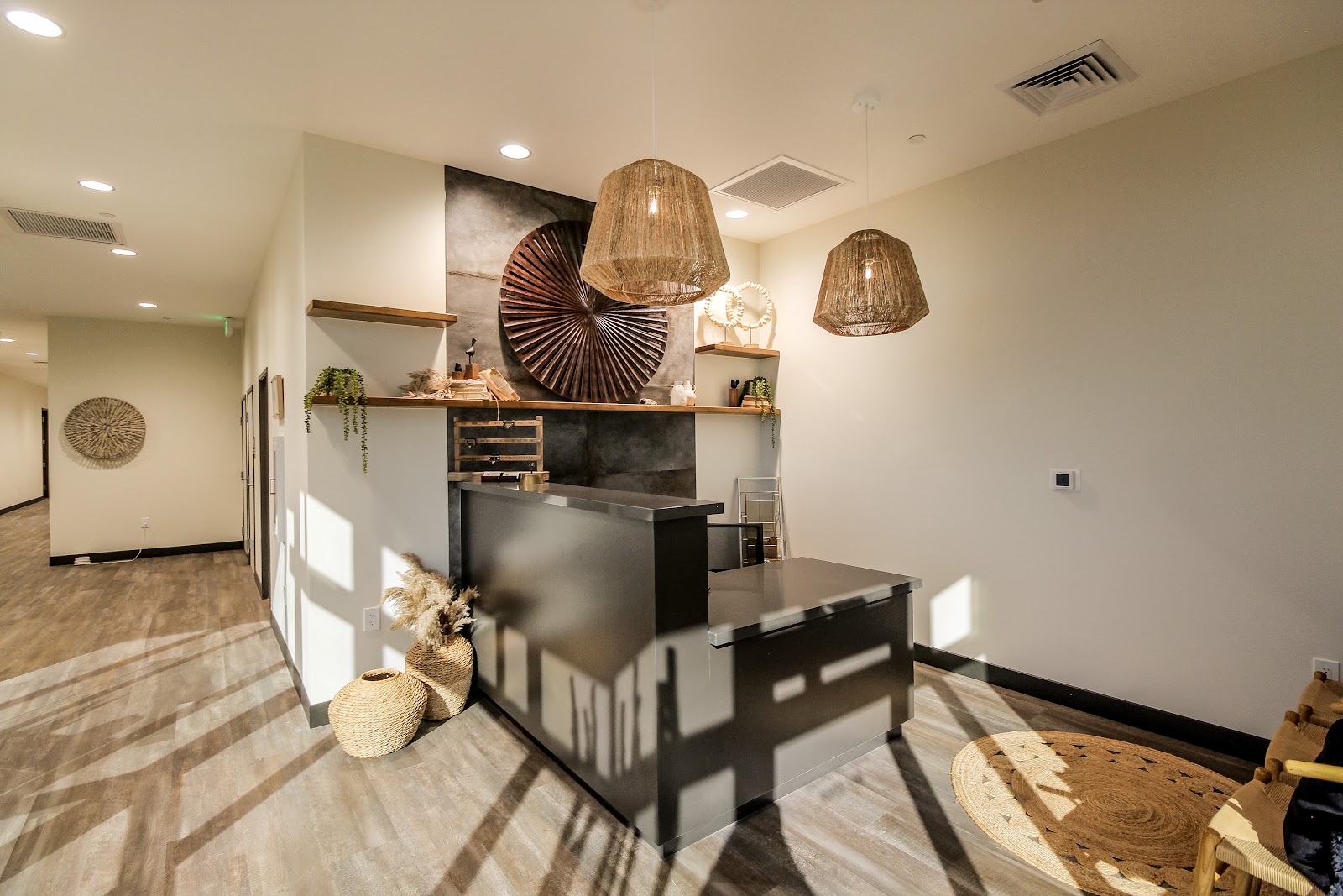 Interior reception area with decorative pendant lights, ornamental sculpture, shelving, and landscape artwork.