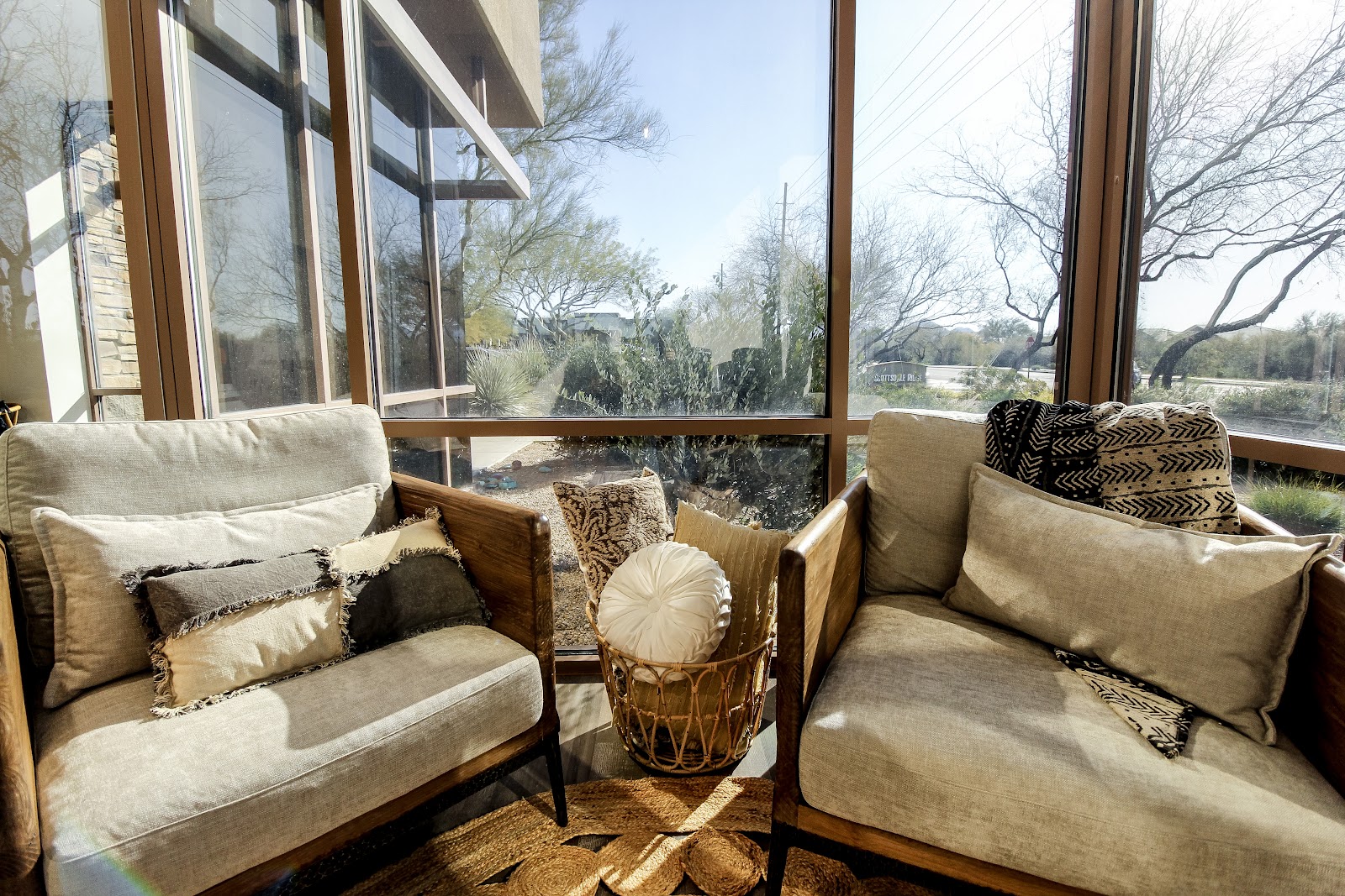 Interior seating area with upholstered armchairs, patterned pillows, and large windows overlooking landscaped grounds.