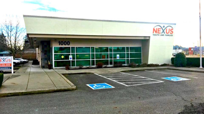 Accessible parking spaces and facility storefront with green-tinted glass windows and entrance area