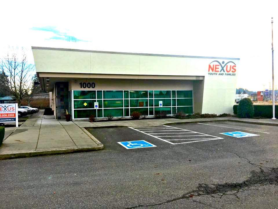 Accessible parking spaces and facility storefront with green-tinted glass windows and entrance area