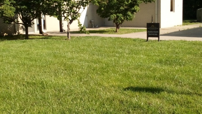 Exterior of modern treatment facility with white brick construction, covered pergola, and manicured landscaping with trees