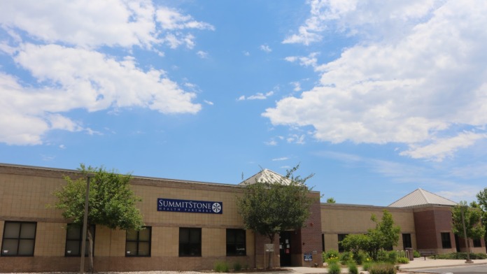 Exterior view of SummitStone Health Partners administrative office building with brick and tan facade, prominent signage, landscaping, and parking area