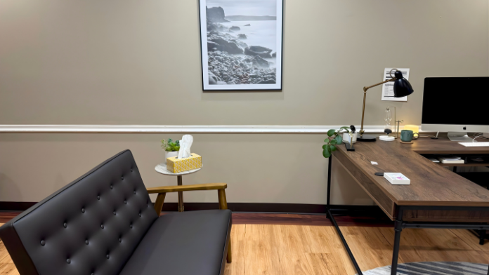 Interior office with desk, black office chair, framed landscape artwork, desk lamp, and motivational wall signage