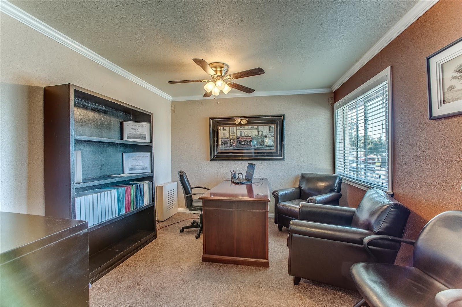 Interior office area with desk, leather seating, bookshelf, and artwork on walls for client consultations