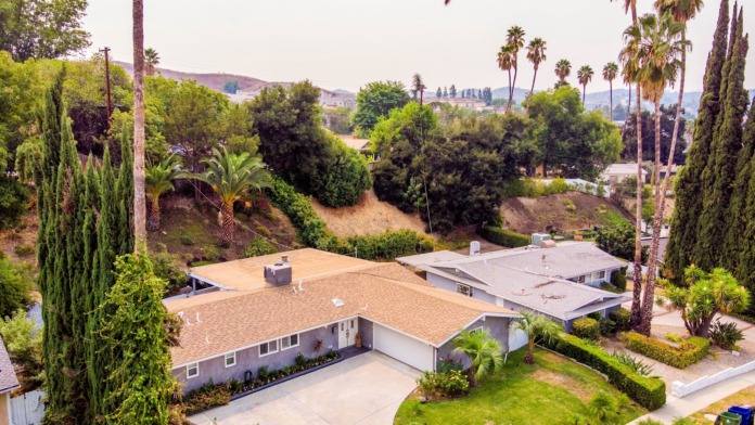 Aerial view of multi-building treatment facility complex on hillside with landscaped grounds and cypress trees.