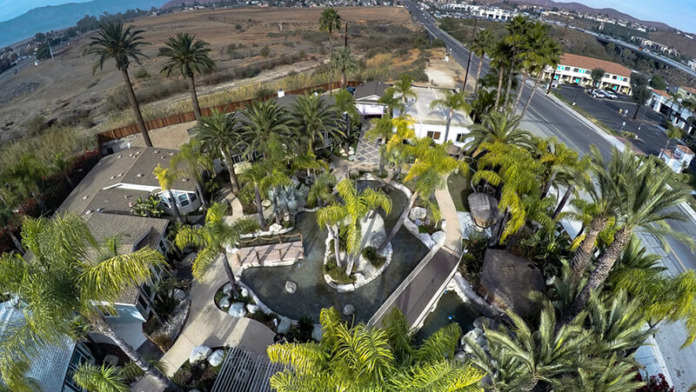 Exterior aerial view of treatment center with palm trees, landscaped grounds, parking area, and surrounding landscape