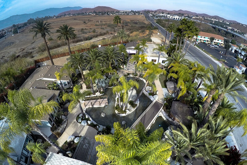 Exterior aerial view of treatment center with palm trees, landscaped grounds, parking area, and surrounding landscape