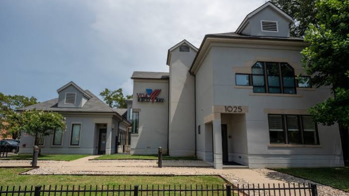 Exterior view of gray and white modern residential building with multiple peaked roofs, windows, and grounds
