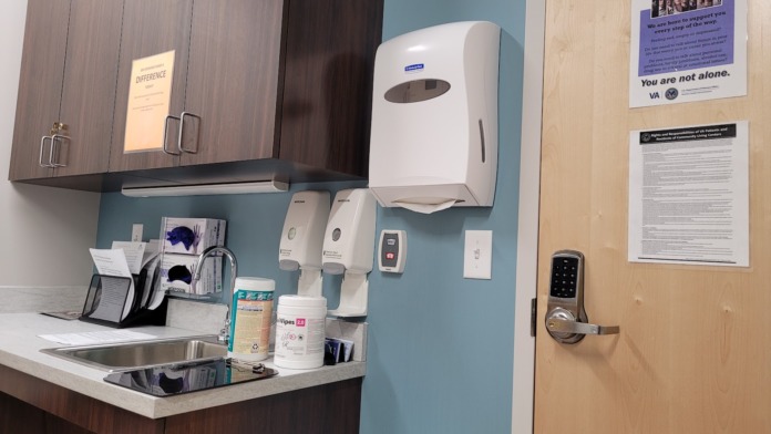 Interior restroom facility with sink, paper towel dispenser, and support resource materials on walls