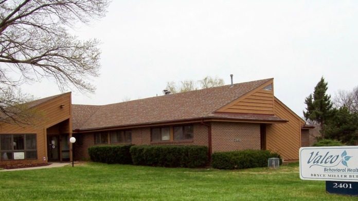 Brick and tan exterior of Bryce Miller Building with landscaped grounds and flagpole