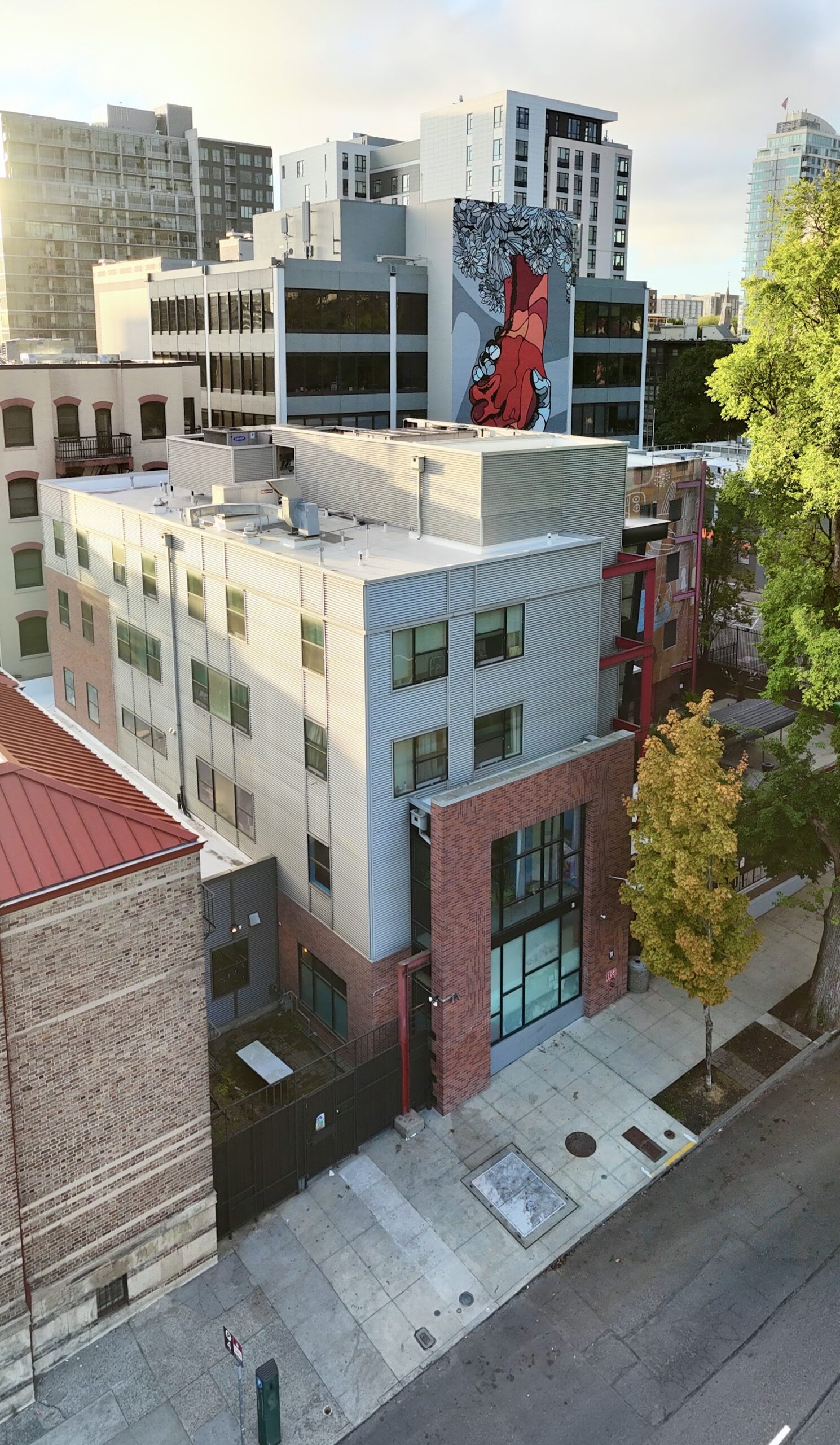 Aerial view of modern facility building with white and light blue exterior and red metal framing
