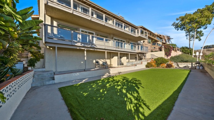 Exterior view of multi-story facility with green lawn, landscaping, and architectural features
