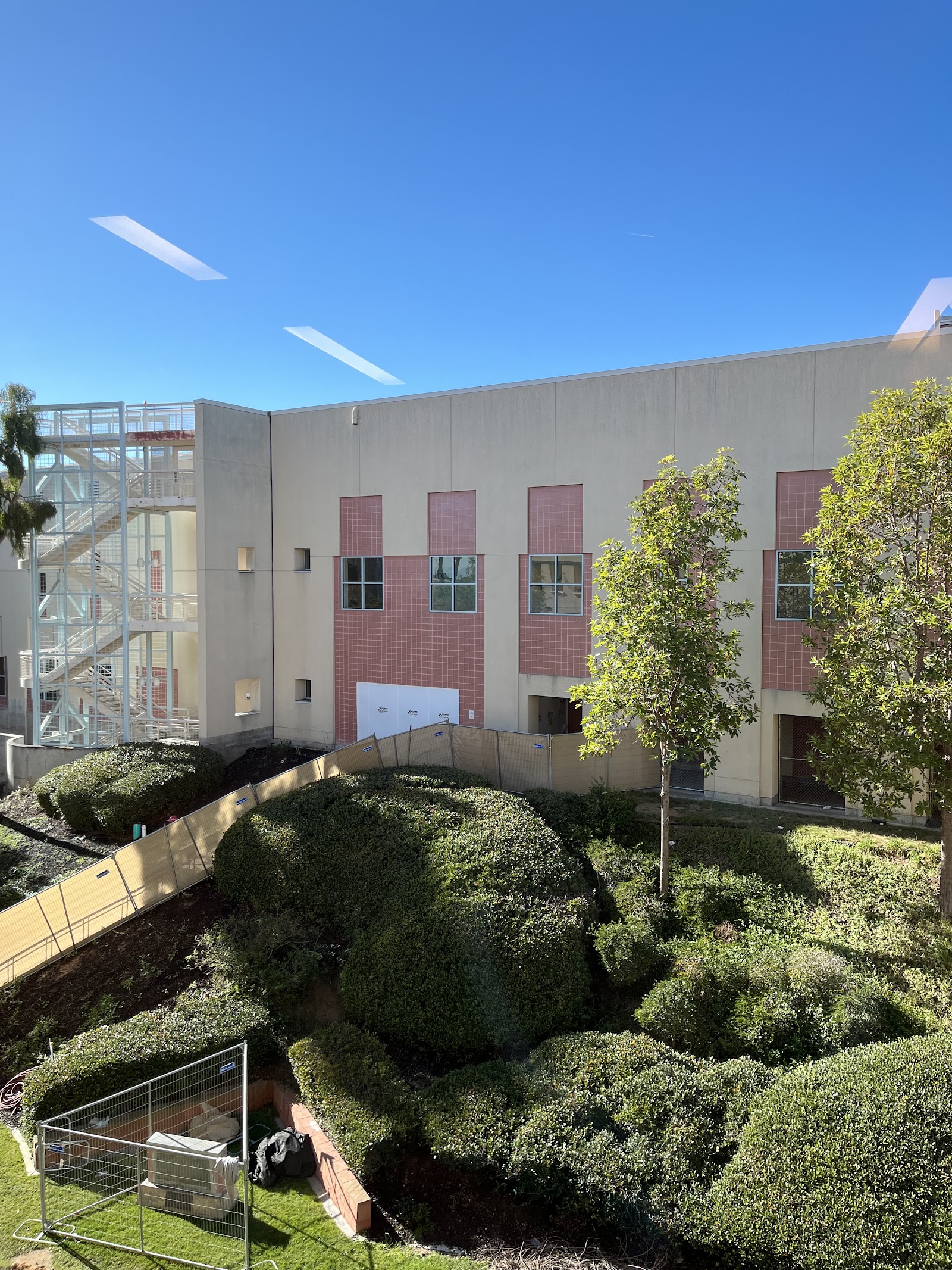 Exterior view of modern hospital building with red tile details, landscaping, and architectural features
