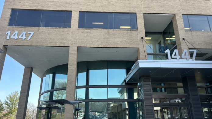 Exterior multi-story brick and glass building with large windows and visible address number 1447 signage