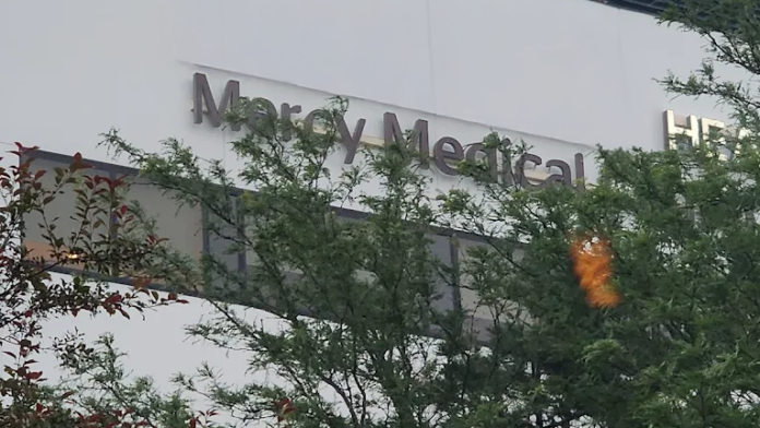 Exterior close-up view of Mercy Medical signage on white building facade with green landscaping and shrubs
