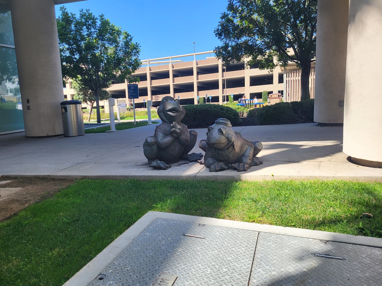 Outdoor campus area with animal statues, grass, trees and modern building structures visible