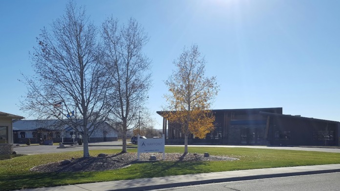 Exterior campus view showing multiple buildings, landscaped grounds with bare trees, and open green spaces.