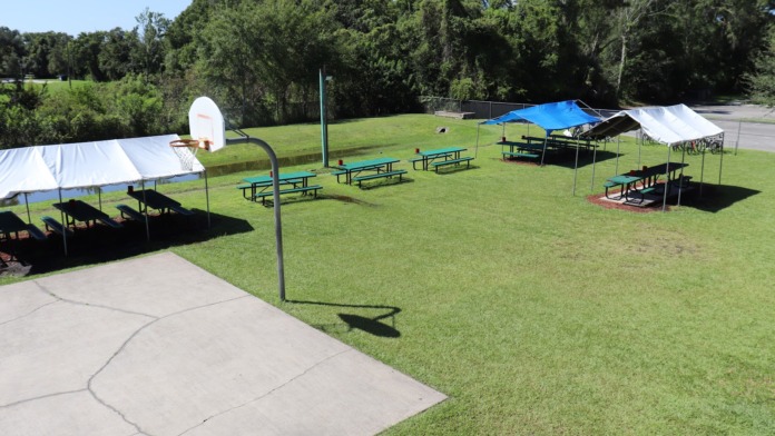 Exterior canteen shelter with Coca-Cola vending machines, white fence, and landscaping