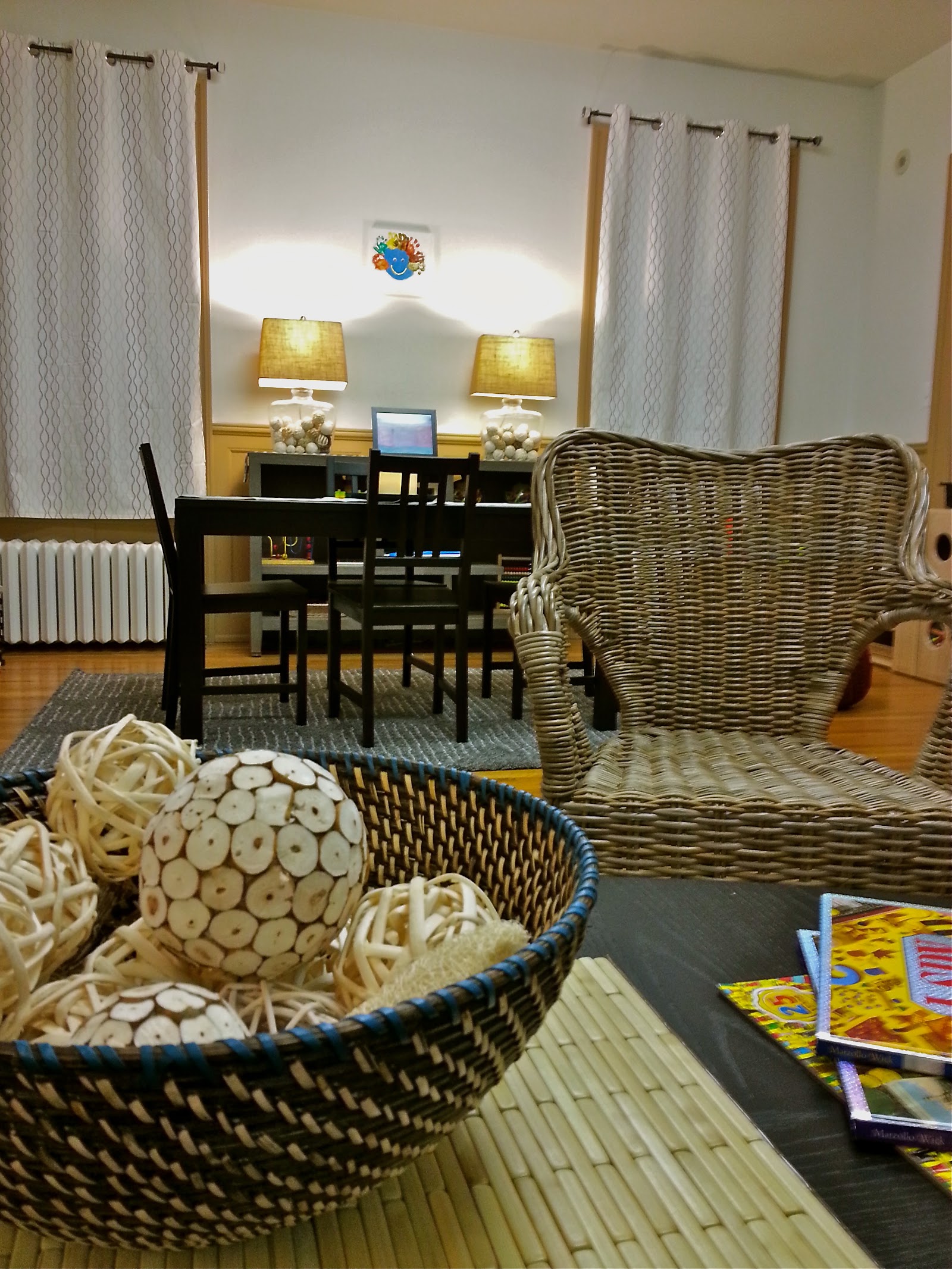 Interior lounge space with wicker furniture, white lamps with yellow shades, storage baskets, and children's activity areas