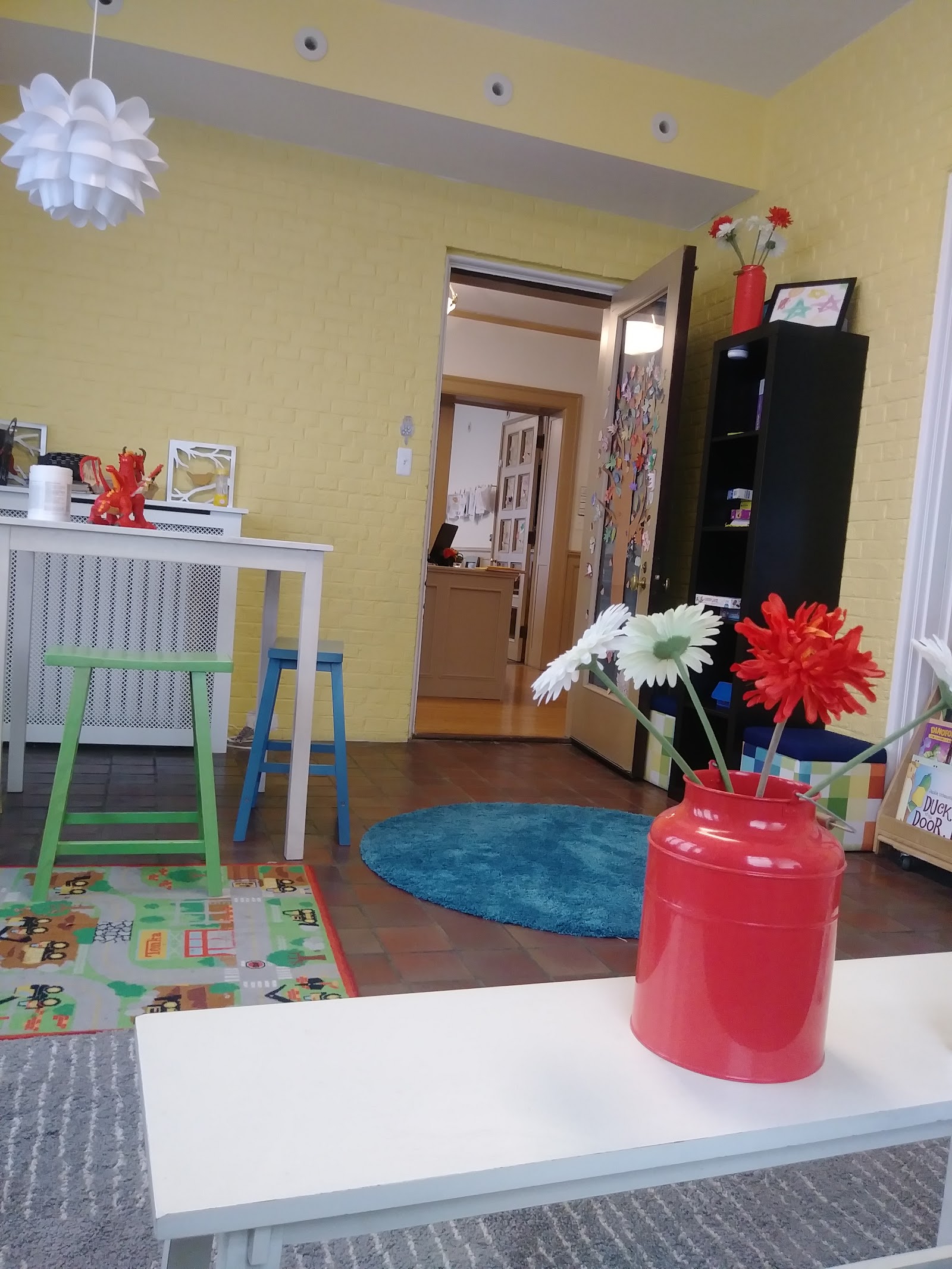 Interior playroom with yellow walls, colorful decorations, toys, seating areas, and child-friendly furniture and design