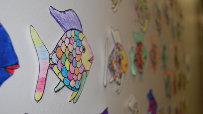 Interior wall displaying colorful children's artwork including colorful fish and artistic drawings