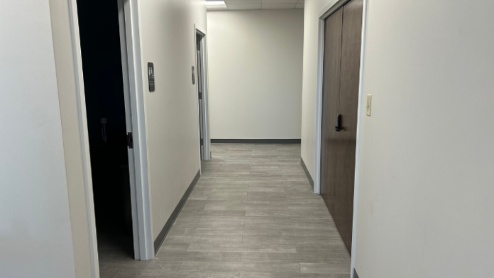 Interior corridor with light walls, vinyl flooring, white door trim, and recessed ceiling lights in clean hallway