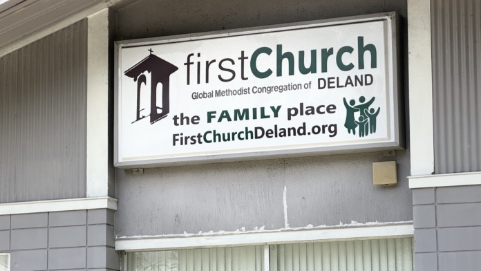 Close-up exterior view of facility signage mounted on building facade with landscaping visible below