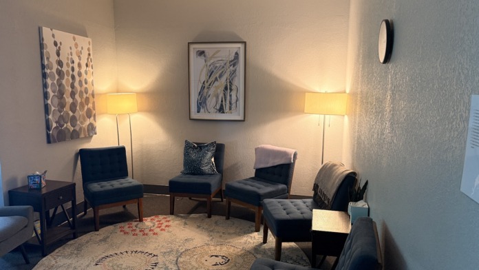 Interior lounge space with multiple comfortable chairs, side tables, warm lighting, framed artwork, and floor rug