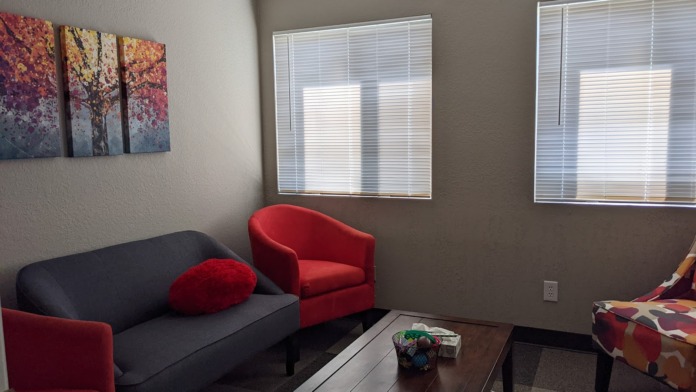 Interior room with black and red sofa, red accent chair, brown coffee table, and autumn forest wall art.