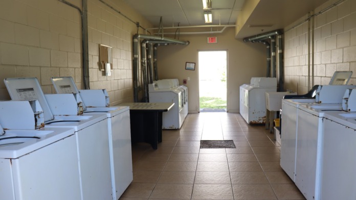 Interior laundry room with multiple commercial washers and dryers, tiled floor, and bright lighting