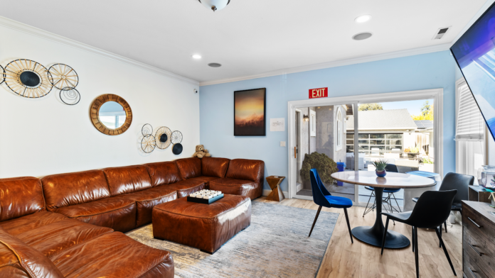 Interior common room with brown leather sectional sofa, dining table, blue accent walls, and decorative art
