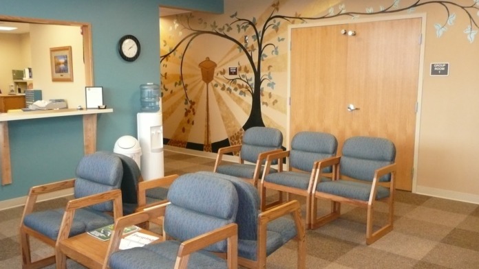 Interior common area with decorative tree mural, wooden furniture, blue upholstered seating, and reception desk