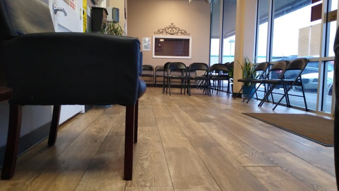 Interior common room with black furniture, wooden flooring, large windows with natural light, and walls with decorative elements