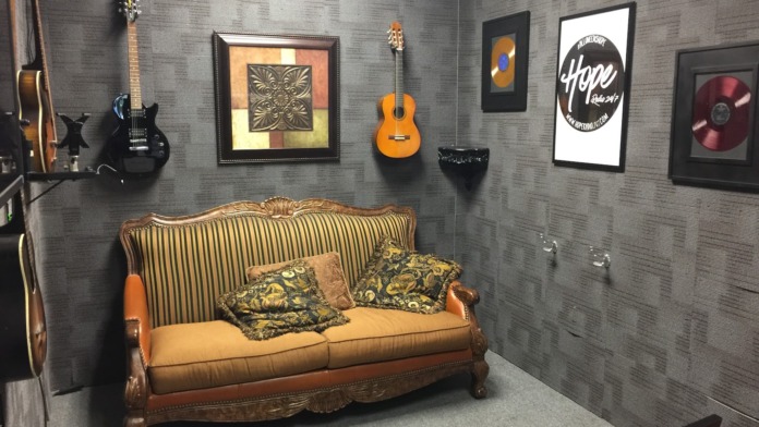 Interior common area featuring leather sofa, mounted guitars, framed artwork, and vintage decor on textured walls