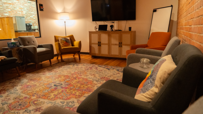 Interior lounge space with upholstered seating, television, brick walls, and patterned flooring