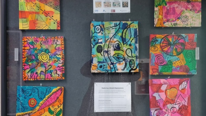 Interior wall display featuring colorful painted artwork panels with vibrant patterns and inspirational expressions, mounted as therapeutic artwork