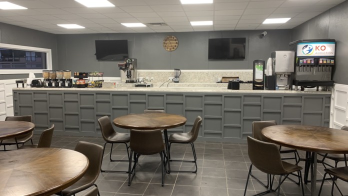 Interior break room with counter seating and round dining tables with beverage station