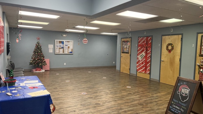 Interior event space with decorated Christmas tree, blue catering table, wrapped doorways, and wood flooring