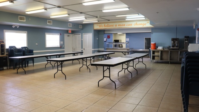 Interior community room with multiple tables, chairs, and inspirational signage on blue walls