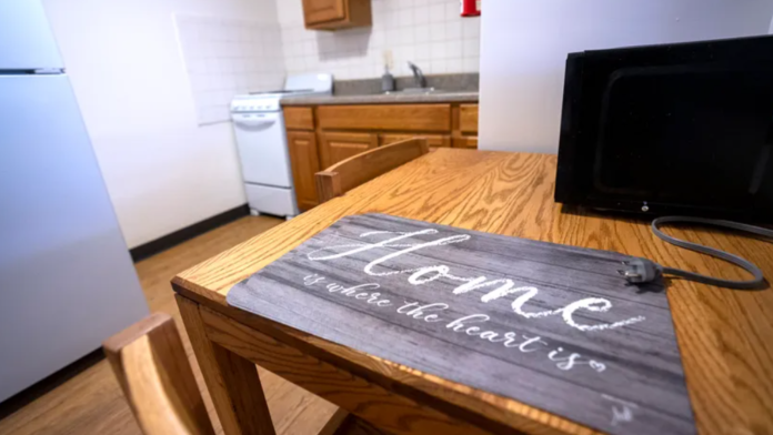 Interior kitchen with wooden dining table, white appliances, and television in residential treatment setting