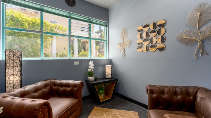Interior common area with leather seating, decorative plants, wooden accents, and facility signage