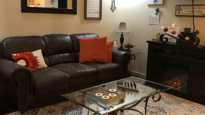 Interior lounge area featuring dark leather sofa, decorative pillows, glass coffee table, fireplace, and inspirational wall signage