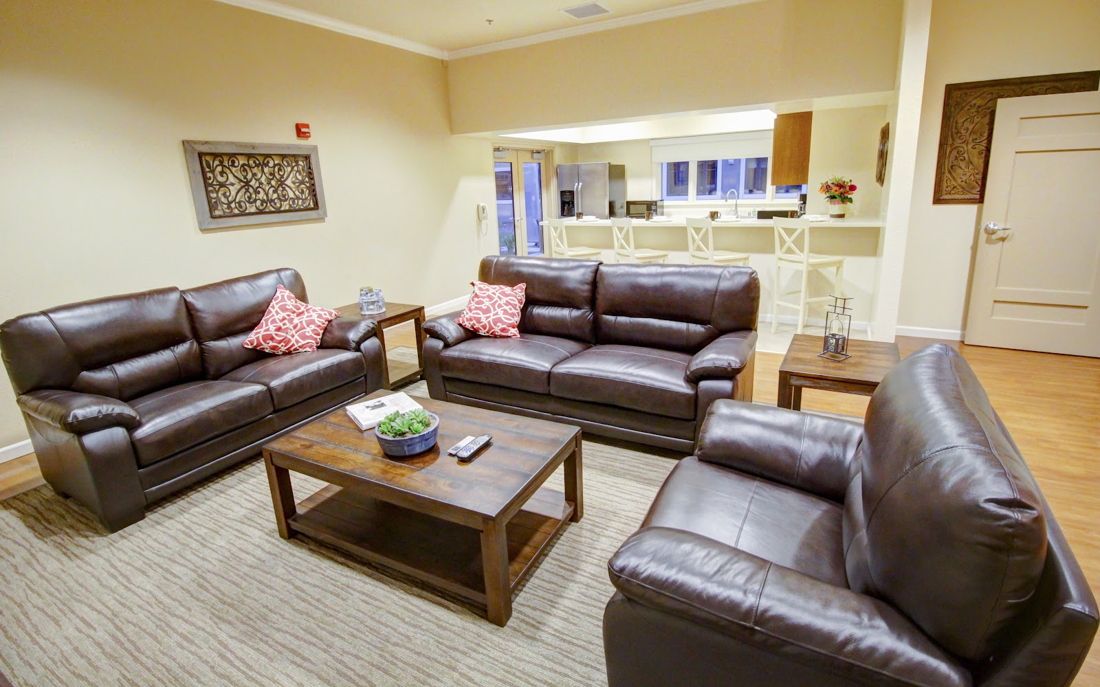 Interior lounge area with brown leather couches, wooden coffee table, decorative wall art, check-in counter, and large windows