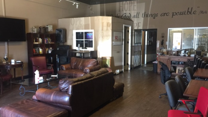 Interior open space with leather furniture, bookshelves, TV, inspirational wall messaging, and multiple seating arrangements