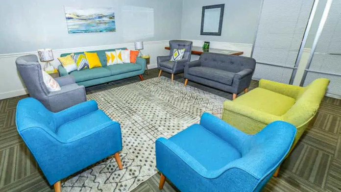 Interior lounge area featuring multiple colorful upholstered chairs and sofas arranged in conversation groupings with patterned area rugs