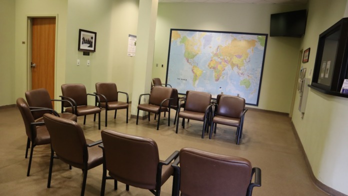 Interior community room with grouped seating, display areas, yellow-green walls, and institutional furnishings for client gatherings