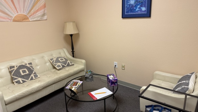 Interior consultation space with cream sofa, round table, framed artwork, and professional furnishings for patient sessions.