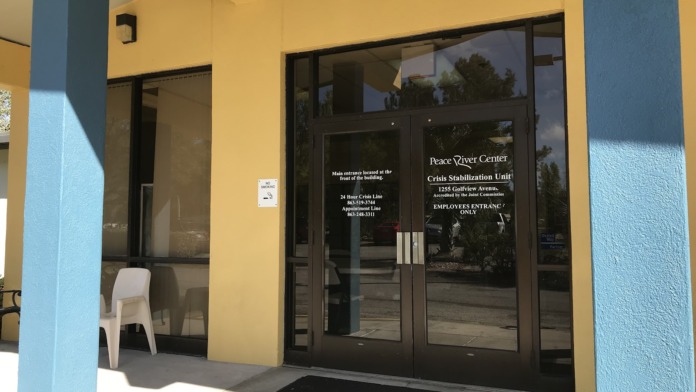 Exterior employee entrance door with facility signage on yellow building with glass doors and blue support columns