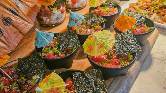 Interior food preparation area with sushi bowls decorated with cocktail umbrellas and kitchen equipment visible