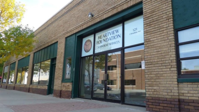 Exterior storefront entrance with glass doors, windows, and facility signage on brick building facade